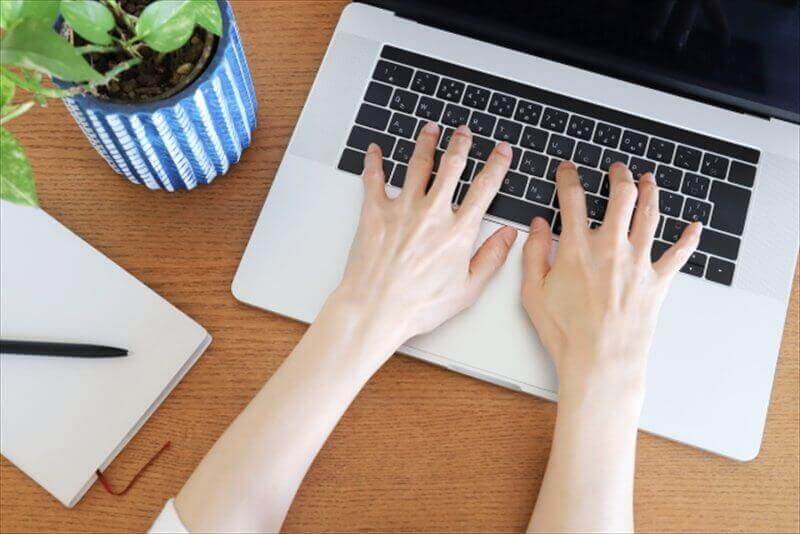 ノートPCでタイピングする手元のクローズアップ—手首角度と肘位置のチェック