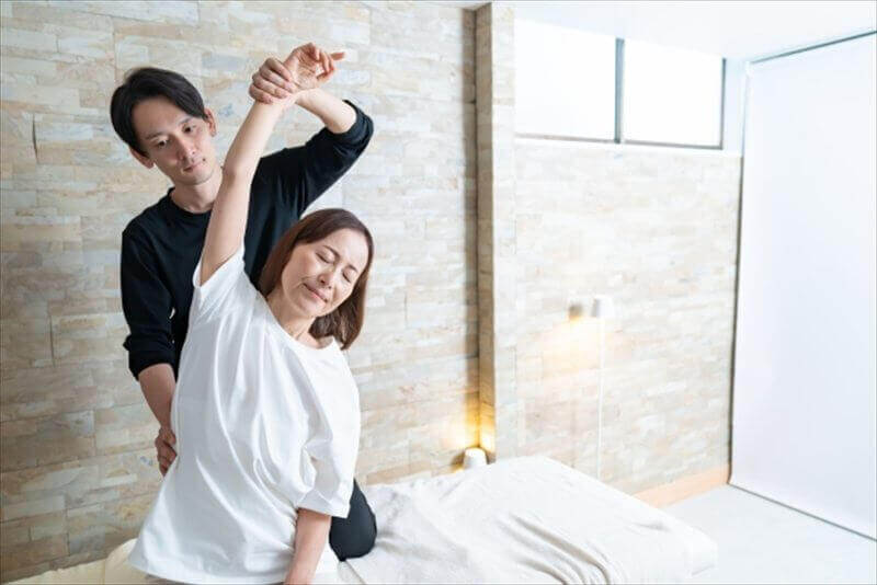 整体を受けて背中を整える女性と施術者