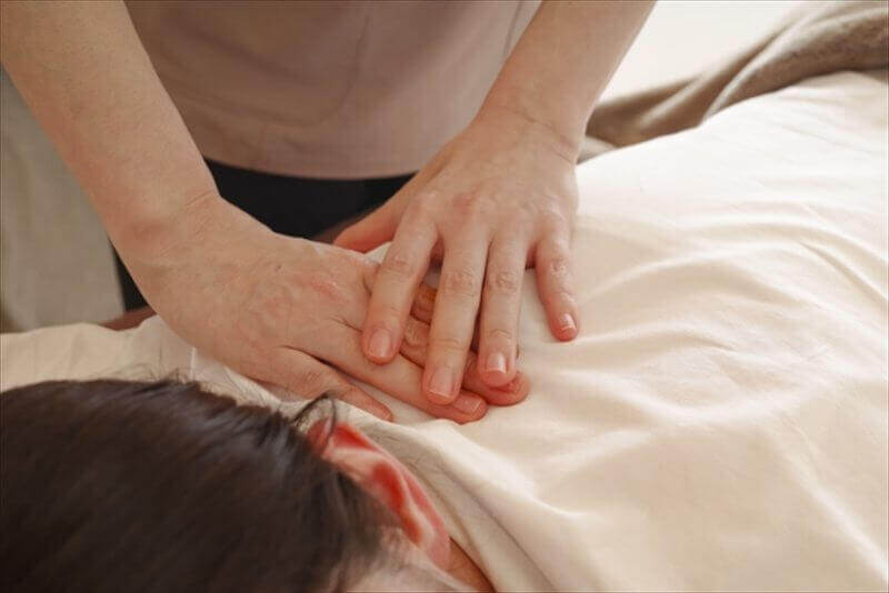 背中に手を当てて丁寧に施術する整体師の手元