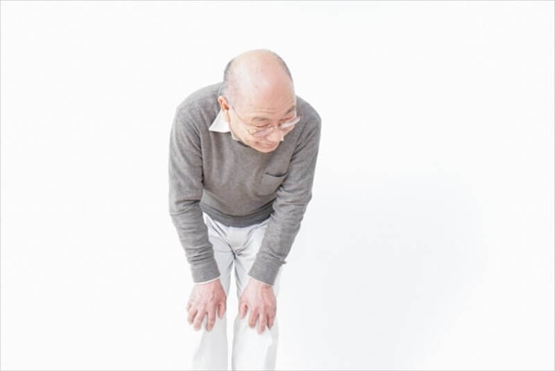 立位で膝に両手を添え前かがみになっている男性