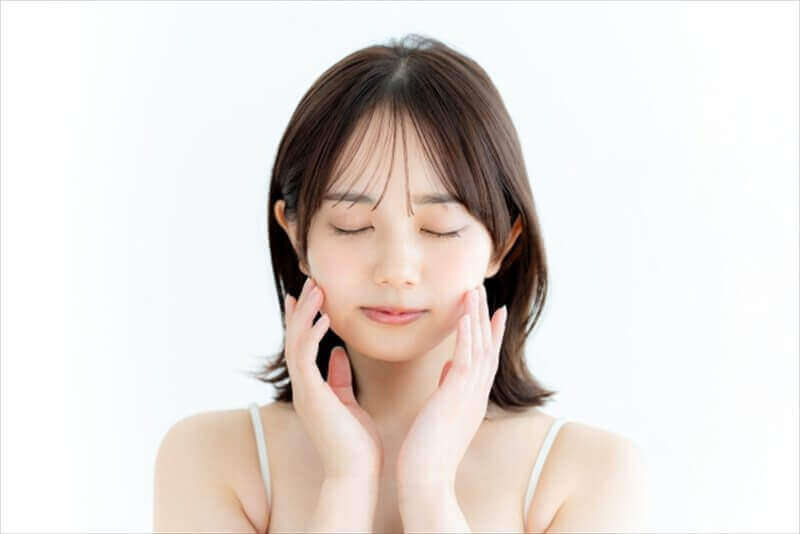 頬に手を添えてあご周りをいたわる女性のクローズアップ(リラックス)