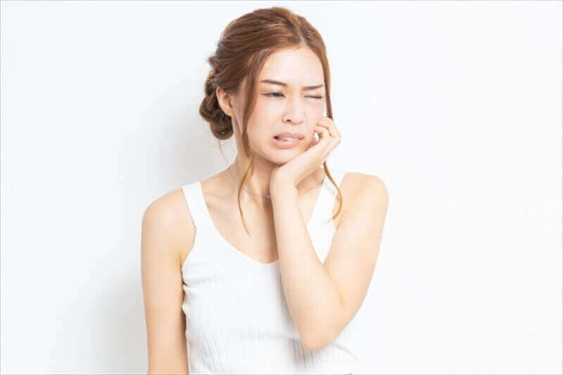 片側の頬に痛みを感じる女性の表情(咀嚼時の顎の痛み)