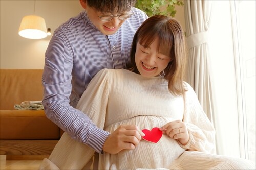 お腹に手を添える妊婦さんと夫婦の微笑ましい姿