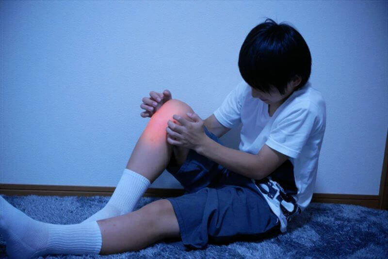 膝の痛みを訴えて座り込む学生