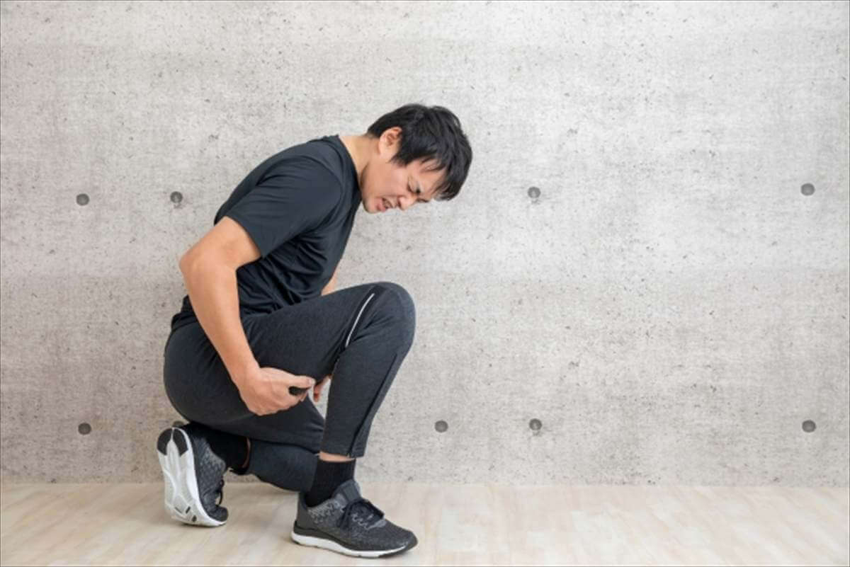 太ももを押さえて苦しむ男性、肉離れによる痛みを表現している様子