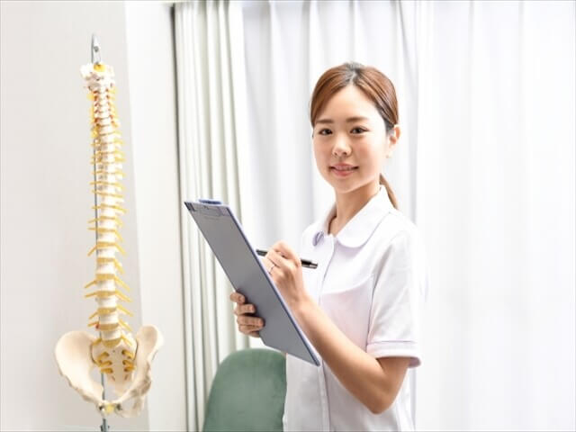 背骨模型の前で説明する整骨院スタッフ