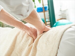 施術中に腰を押さえる整骨院スタッフの手元