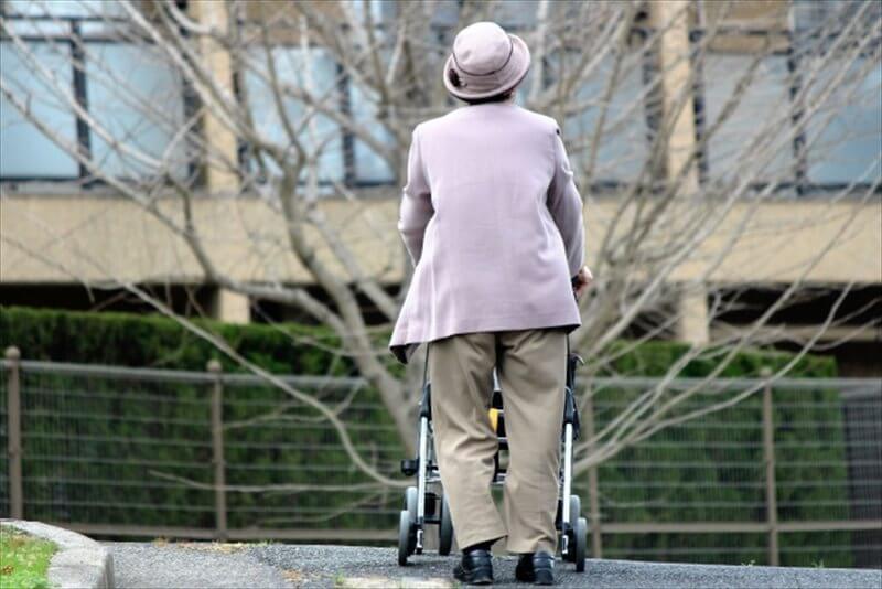 歩行器を押して歩く高齢女性の後ろ姿