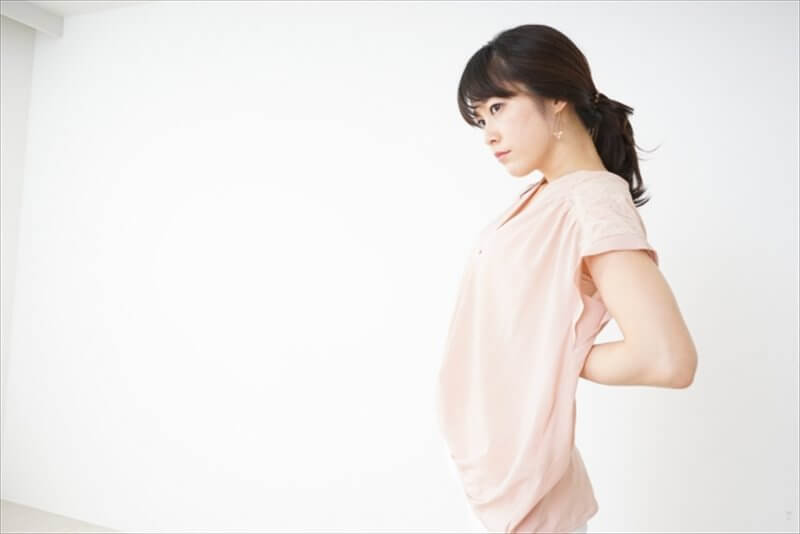 腰痛で体を反らしながら痛みに耐える女性