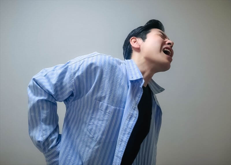 強い腰痛に苦しむ男性の表情と姿勢