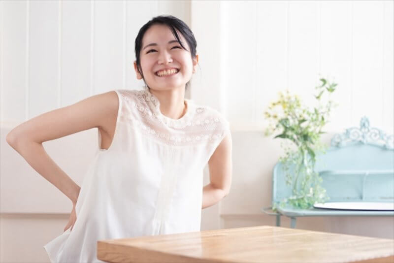 腰に手を当てながら笑顔を見せる女性の姿