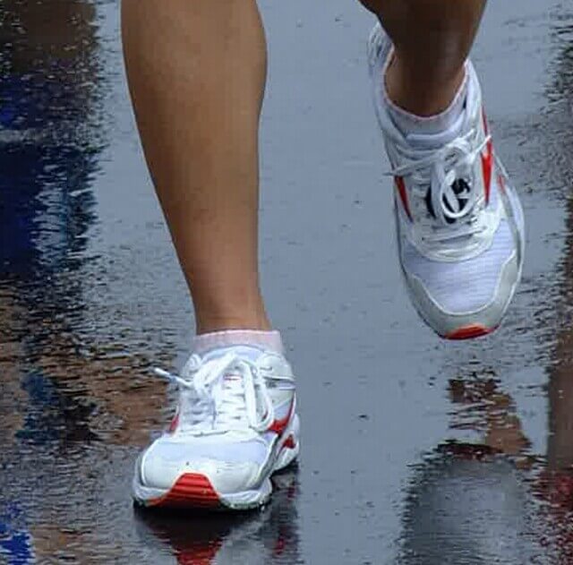 雨の中を走るランナーの足元の写真