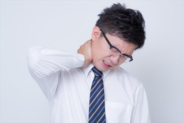 首の痛みに悩むスーツ姿の男性