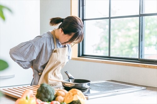 キッチンで腰を押さえる女性
