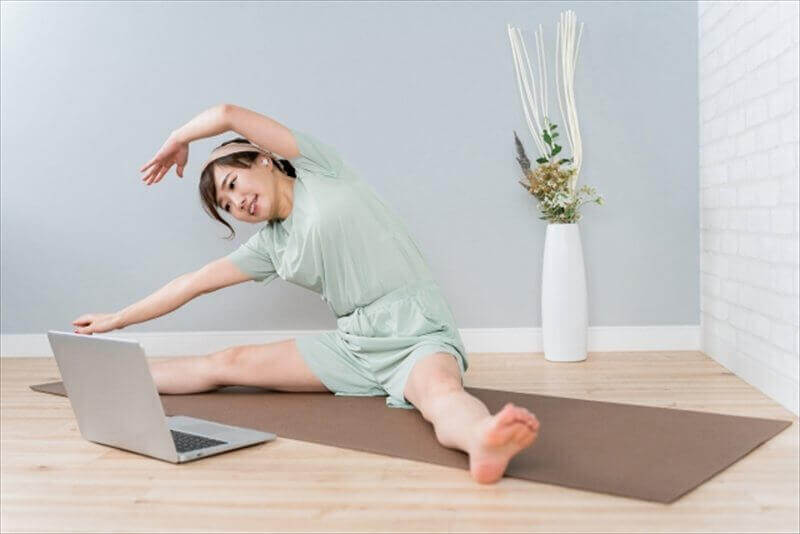 自宅でマットに座りストレッチを行う女性