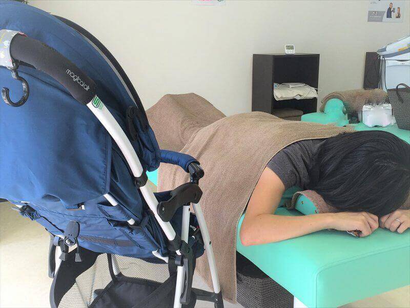 施術ベッドの横にベビーカーを寄せて施術を受ける様子|取手市くまもと整骨院では赤ちゃんをそばに置いたまま通える安心環境を整えています