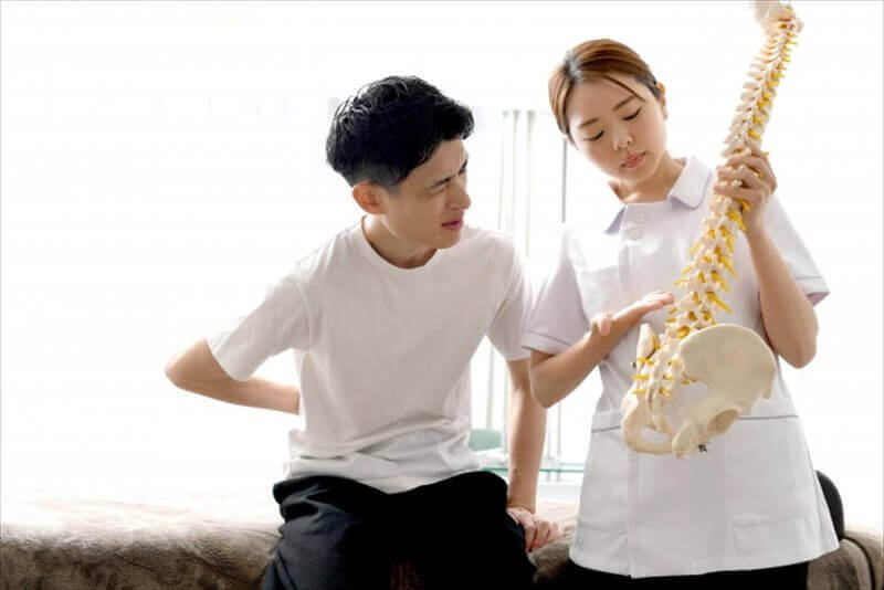 整体スタッフが背骨模型を使って交通事故後の症状を説明する様子