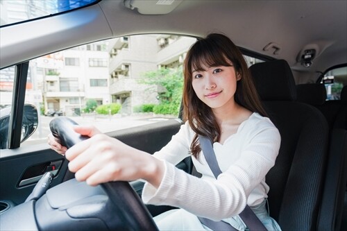 車の運転席に座る若い女性ドライバー