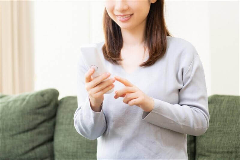 交通事故後の整体予約をスマートフォンで行う女性の写真