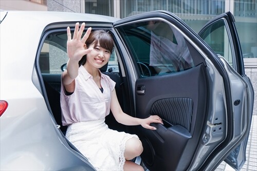 車から笑顔で手を振る女性