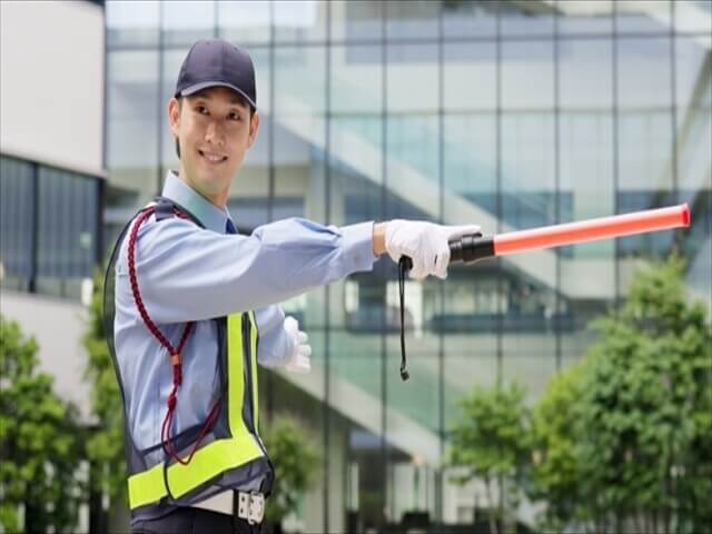 夜間の警備員の男性が誘導棒を持っている